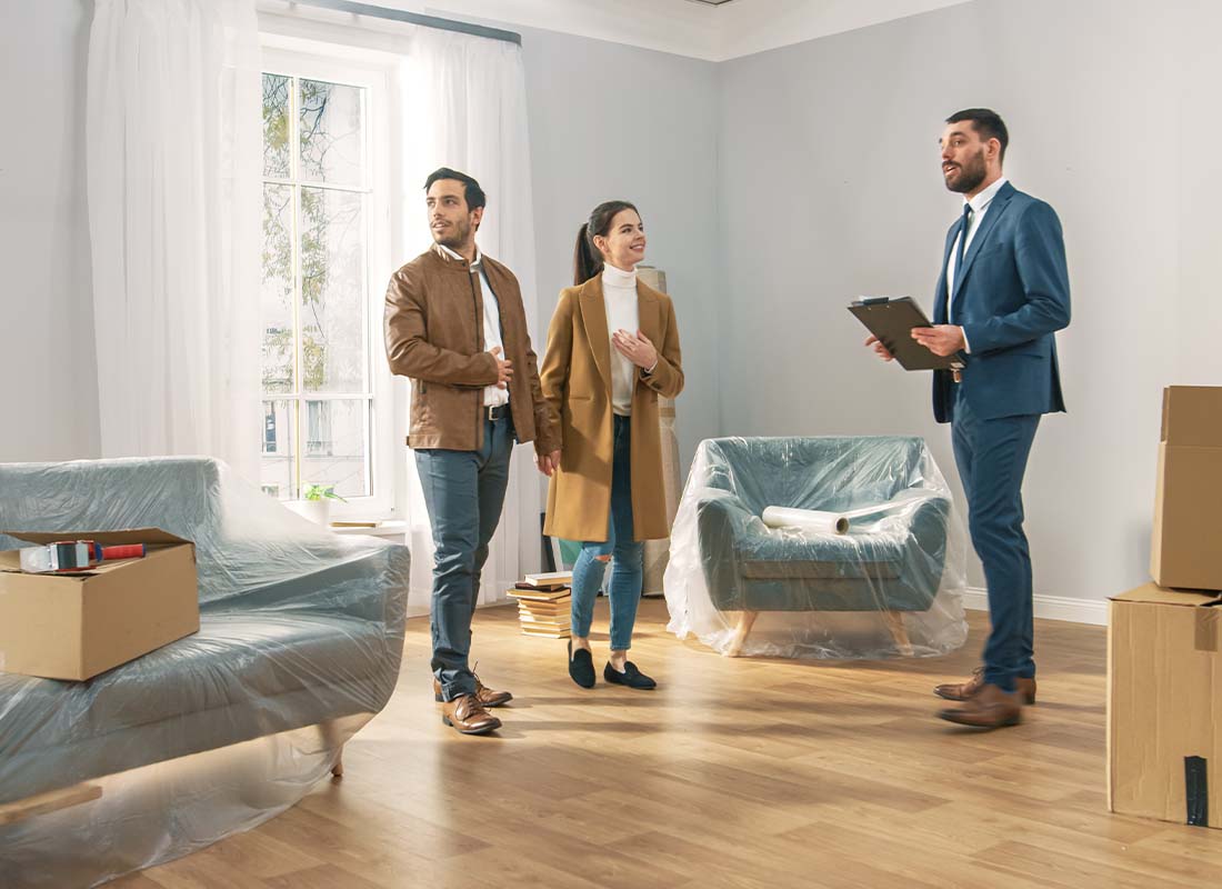 Rental Property Insurance - A Professional Real Estate Agent Shows a Spacious Bright Apartment with Big Windows to a Young Couple