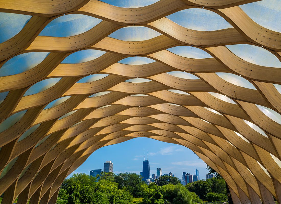 About Our Agency - View of Green Trees and Downtown Chicago Skyscrapers from a Golden Dome Archway in a Park on a Sunny Day