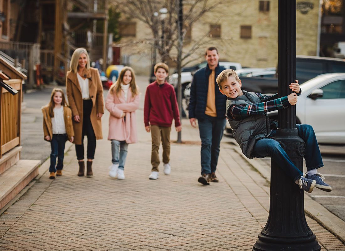 Meet Our Team - Portrait of Agency Owner Brendan Smith and his Family Walking on the Sidewalk in Chicago with One of his Sons Holding onto a Lamppost