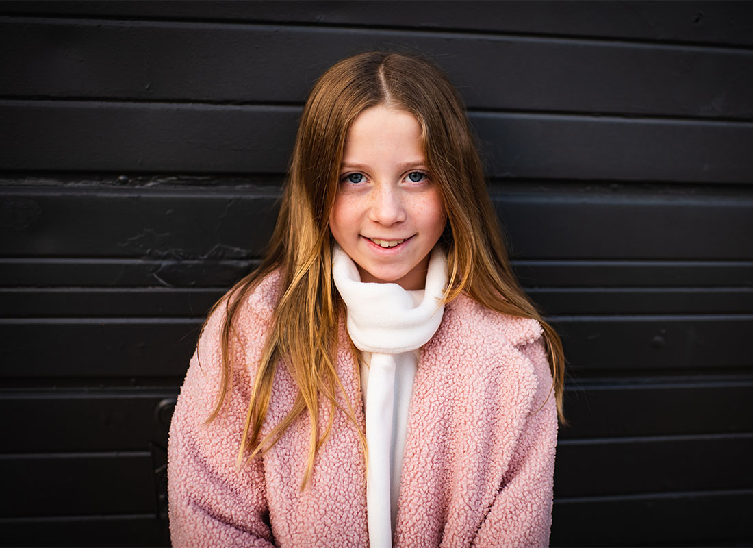 Meet Our Team - Smiling Portrait of Brendan Smith's Oldest Daughter Wearing a Coat and Scarf